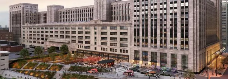 Historic postal building with a modern riverside park and urban activity.