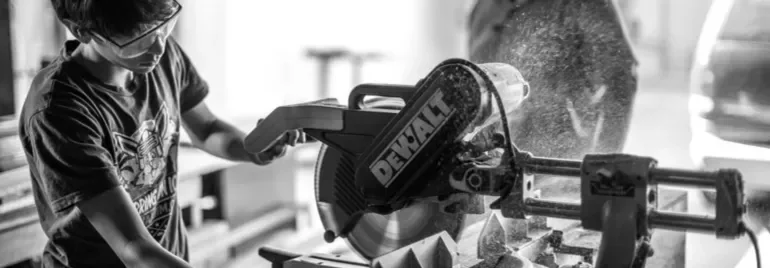 Person operating a circular saw wearing safety goggles.