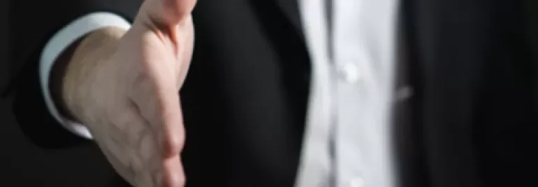 A person in a suit extending a handshake.