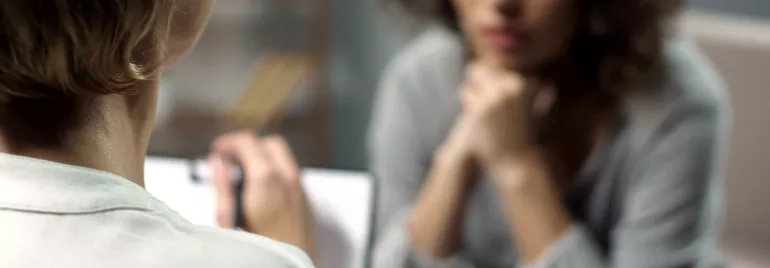 Two people in a discussion, one taking notes, the other listening attentively.