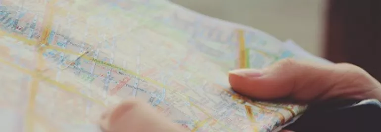 Person holding a folded map with various colorful street lines.