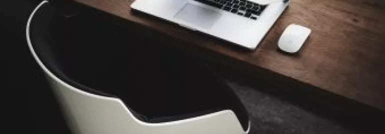 Modern workspace with a laptop and a mouse on a wooden desk.