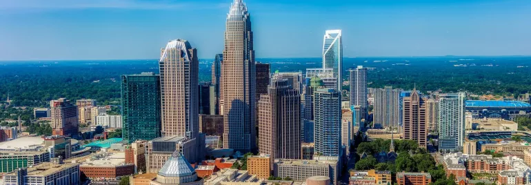 Aerial view of a city skyline with several skyscrapers and a bright blue sky.