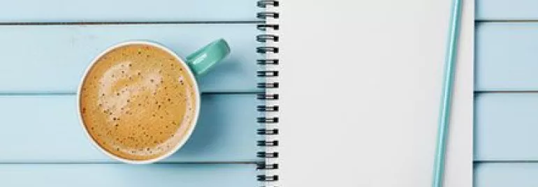 Coffee cup and a to-do list notebook with a pencil on a blue wooden table.