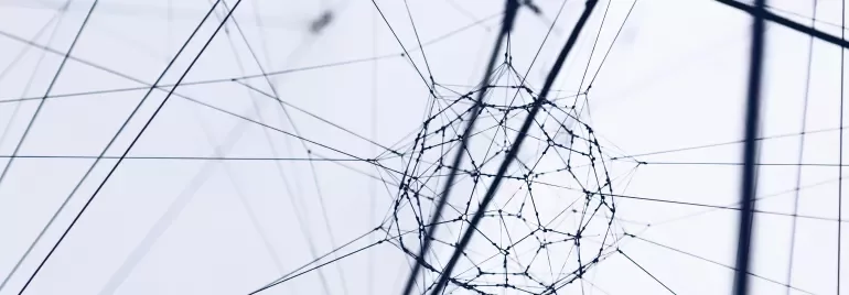 Close-up of a geometric wire structure with intersecting lines on a light background.