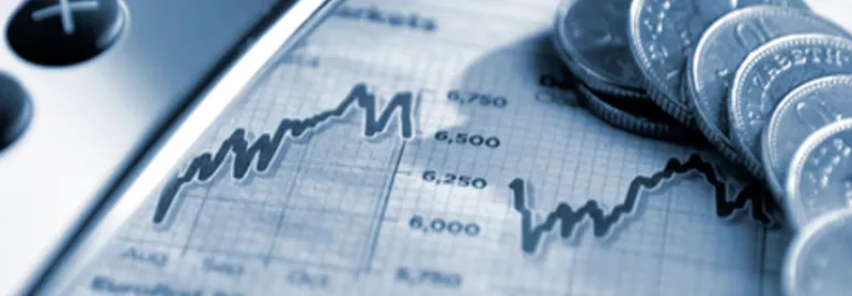 Close-up of coins, a calculator, and a financial graph.