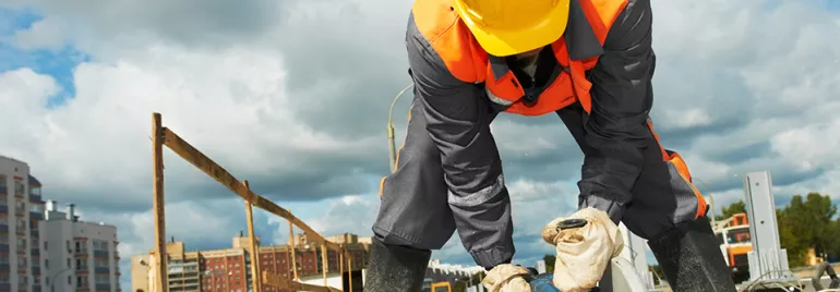 Construction worker cutting metal with a circular saw on a building site.