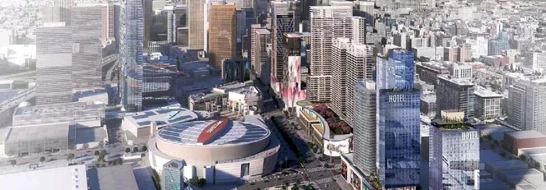 Aerial view of a modern city skyline with tall buildings and a sports arena in the foreground.