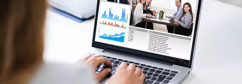 Person on a video call with charts and graphs displayed on a laptop screen.