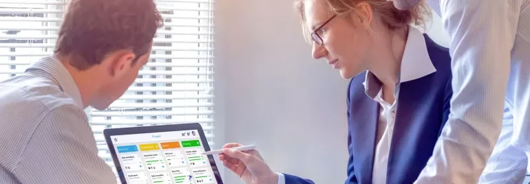 Three colleagues reviewing a project on a laptop in a bright office.
