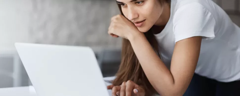 Woman in a white shirt using a laptop at a desk.