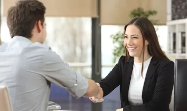 Two people shaking hands in an office setting.