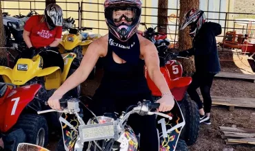 Person with helmet on an ATV, ready to ride.