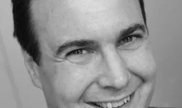 Black and white photo of a smiling person in a suit.