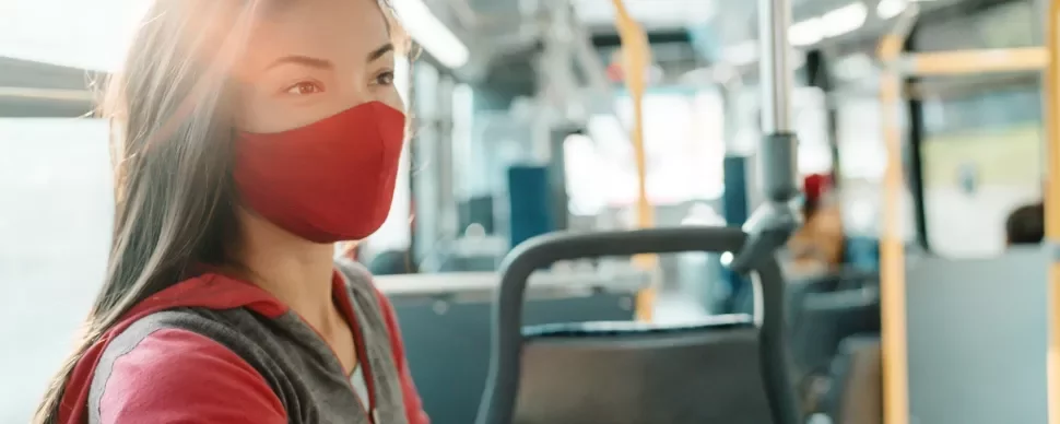 Woman wearing a red mask sitting on a bus