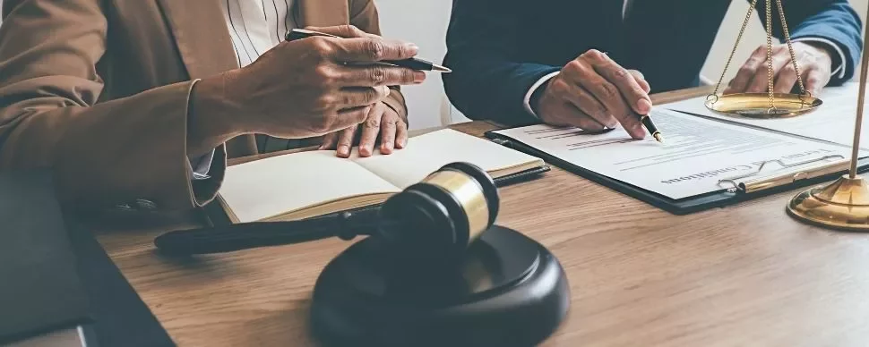 Two professionals discussing documents at a table with a gavel and scales.