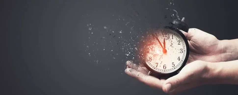 Hands holding a dissolving clock with red glow, symbolizing passing time.