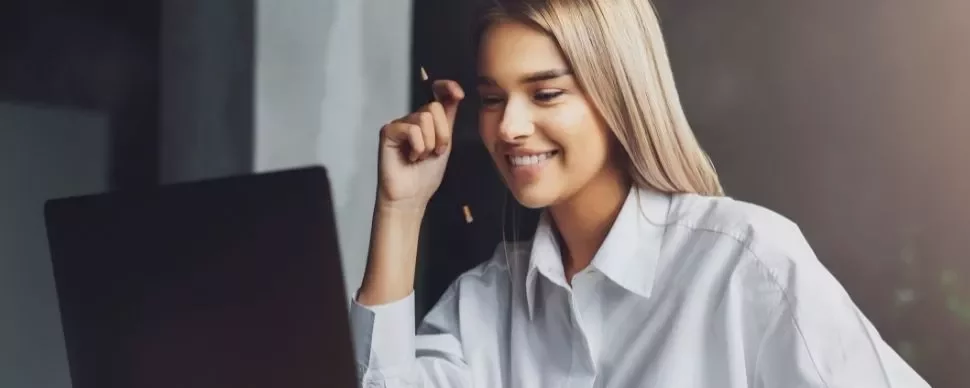 Woman smiling while looking at laptop screen.