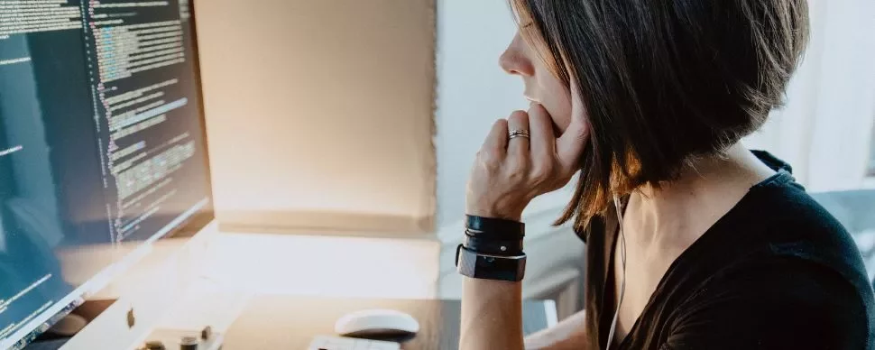 Woman working on code at a computer desk