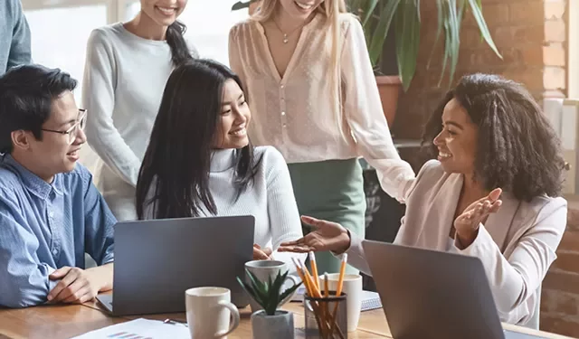 Diverse group of colleagues brainstorming at a table with laptops and coffee.