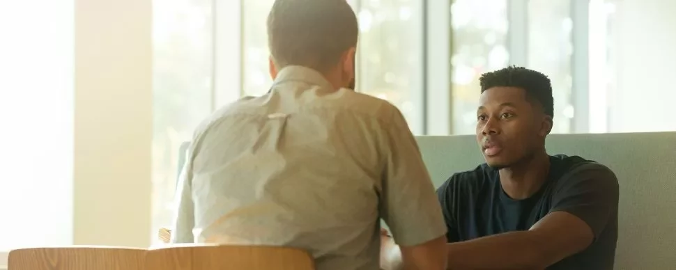 Two men sitting at a table engaged in a conversation.