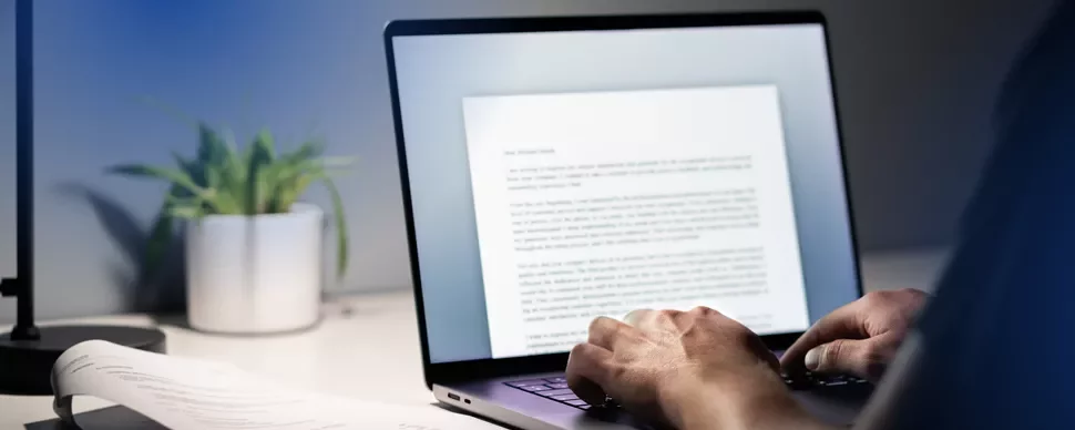 A man typing a resignation letter on a laptop