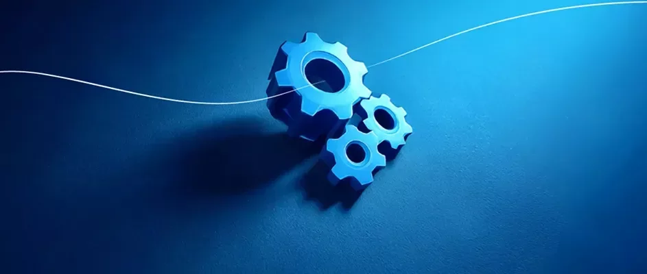 Three blue mechanical gears positioned on a dark blue surface, highlighted by a white flowing line suggesting engineering, mechanics, and precision.