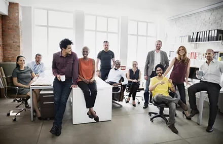 Group of diverse coworkers smiling in a bright office space.