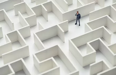 Businessman standing in a large maze, contemplating directions.