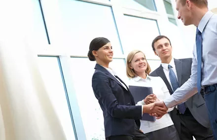 Business professionals shaking hands in a bright office setting.