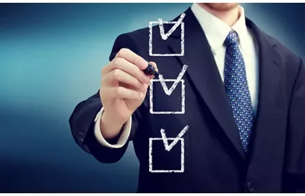 A man in a suit marking checkboxes on a transparent board.