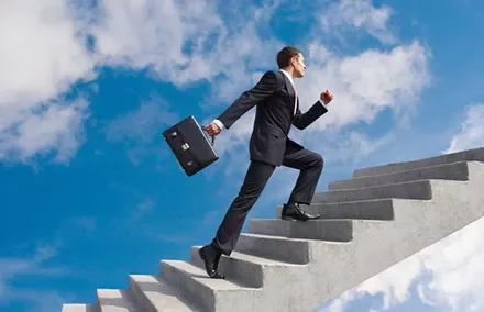 Man in a suit climbing stairs into the sky with a briefcase.