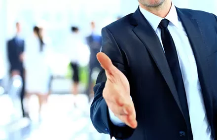 Businessman in a suit reaching out for a handshake.