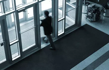 Blurred silhouette of a person exiting through glass doors.