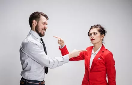 Man and woman in an argument pointing at each other.