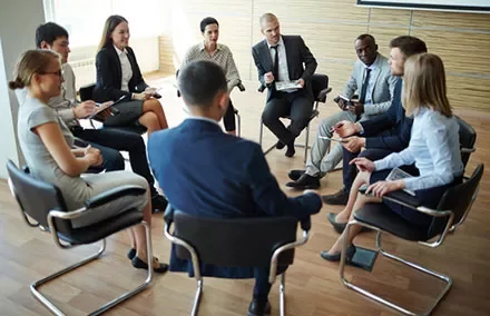 A group of business professionals in a meeting sitting in a circle.