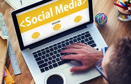 Person using a laptop with a social media screen, coffee nearby.