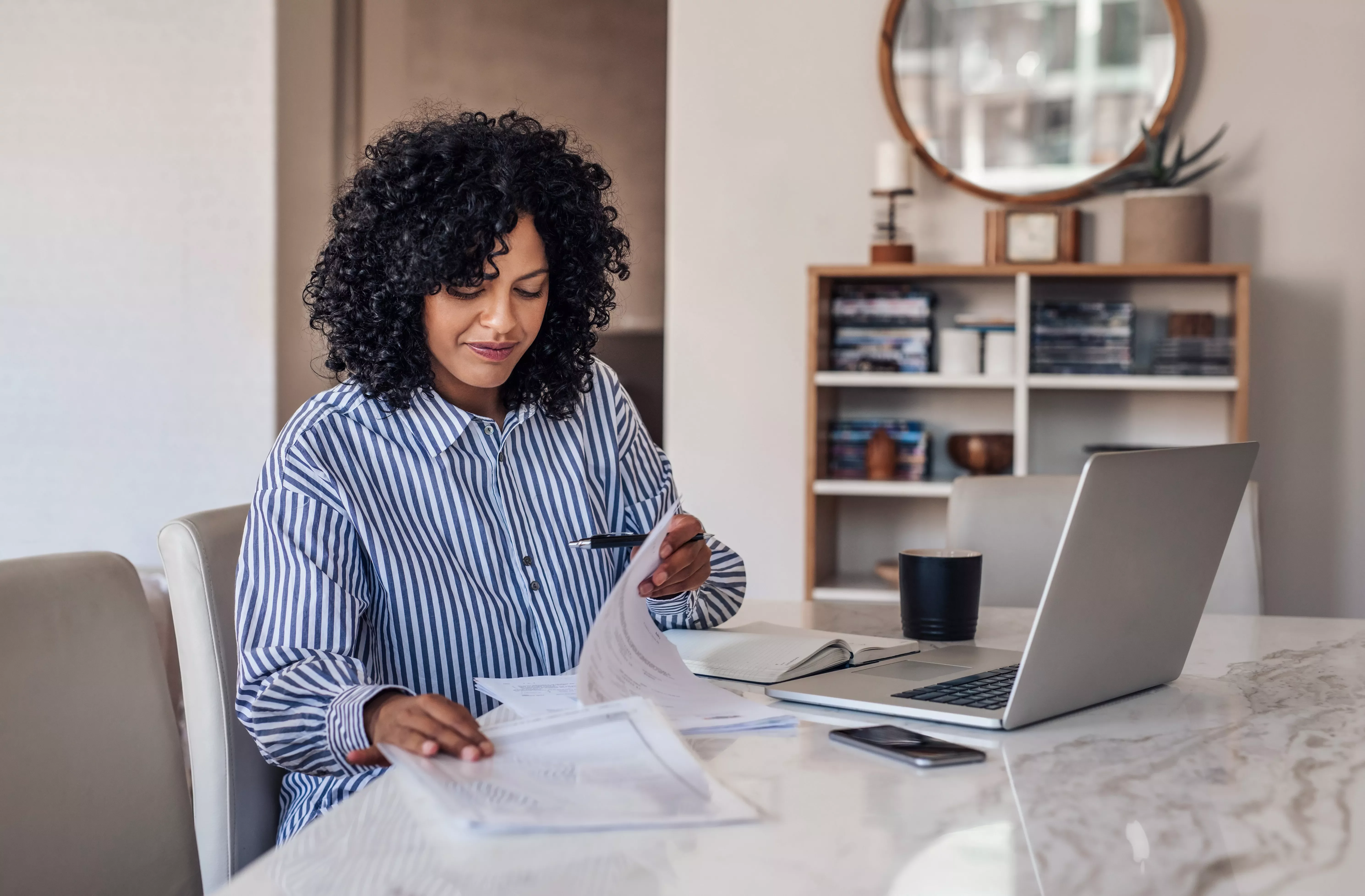 Person working at a table with documents and a laptop.