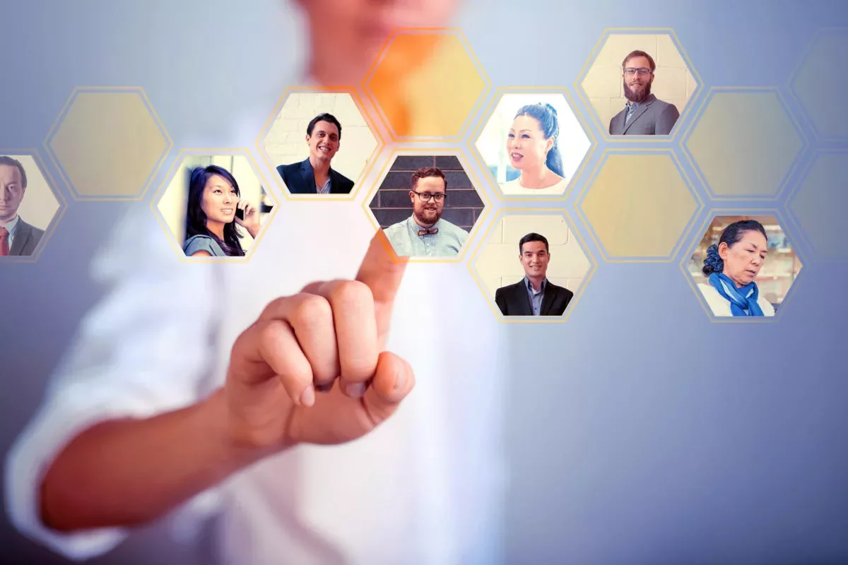 Person touching digital hexagonal interface with portraits.