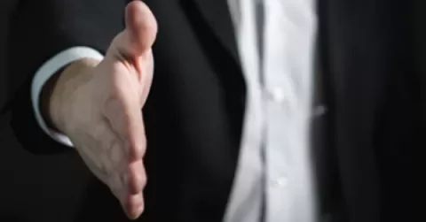 A person in a suit extending a handshake.