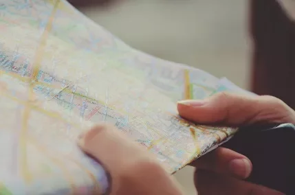 Person holding a folded map with various colorful street lines.