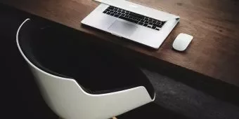 Modern workspace with a laptop and a mouse on a wooden desk.