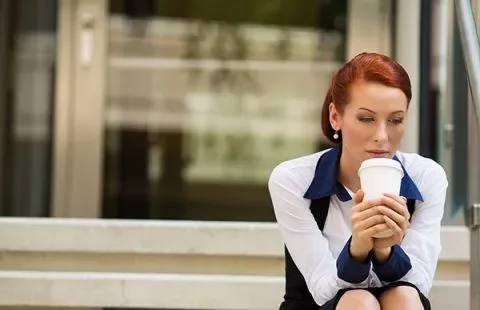 Woman sitting on outdoor steps holding a coffee cup.