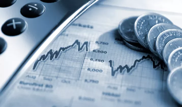 Close-up of coins, a calculator, and a financial graph.
