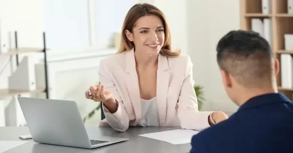 Woman in a business meeting with a laptop, smiling at a colleague.